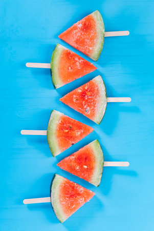 Watermelon slices on a stick on a blue background. Top viewの写真素材