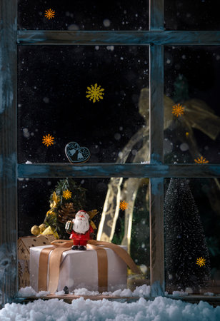 Christmas decoration on the window at night. Santa Claus, gift box and snowflakesの写真素材