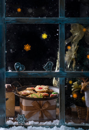 Christmas cookies in the snow on the background of the window with snowflakesの写真素材