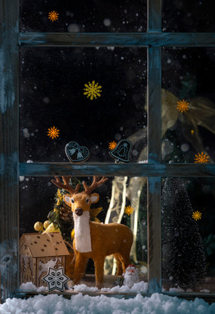 Christmas decoration on the window at night. Christmas tree, snow and deerの写真素材