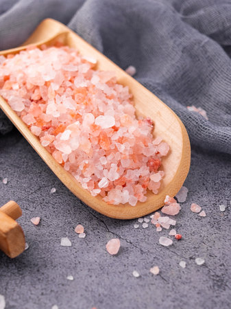 Himalayan salt in wooden scoop on concrete background. Selective focus.の写真素材
