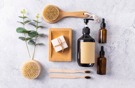 Zero waste bathroom accessories. Natural bamboo toothbrushes, soap, bath salt, shower gel, brush, cotton pads and green leaf on white background. Top viewの写真素材