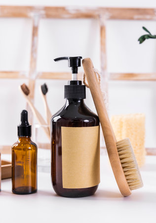 Brown glass bottle with liquid soap, wooden brush and sponge on shelf in bathroomの写真素材
