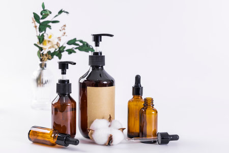 Essential oils in glass bottles and cotton flowers on white background.の写真素材