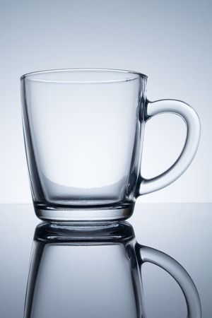 Empty glass cup with reflection on a tableの写真素材