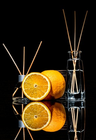 Air fresheners with orange fruits scent in a beautiful glass jars with sticks and whole orange and a...