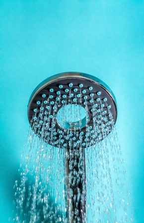 Modern hot shower with stream of water close up on a blue backgroundの写真素材
