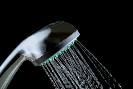 Modern hot shower with stream of water closeup isolated on black backgroundの写真素材