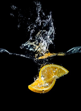 Orange slices falling into the water close-up, macro, splash, bubbles, black backgroundの写真素材