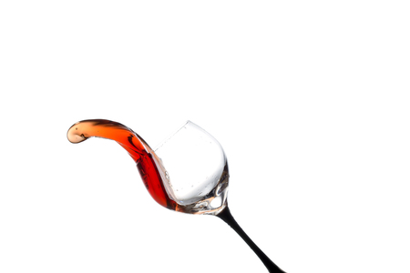 stream of wine being poured out off a glass isolated on a white background