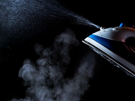 Iron with steam and water stream isolated on a black backgroundの写真素材
