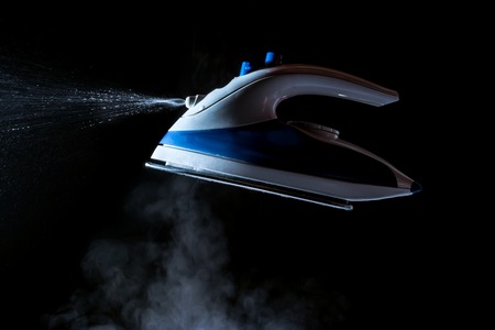 Iron with steam and water stream isolated on a black backgroundの写真素材