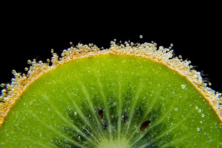 Kiwi sliced water bubbles dark black background texture close-up macroの写真素材