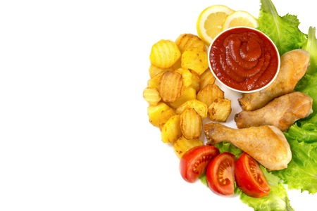 chicken legs on a white plate with slices of tomato and lettuce and french fries and ketchup top view isolated on white backgroundの写真素材