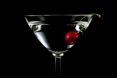 Glass of drink with cherry closeup isolated on black backgroundの写真素材