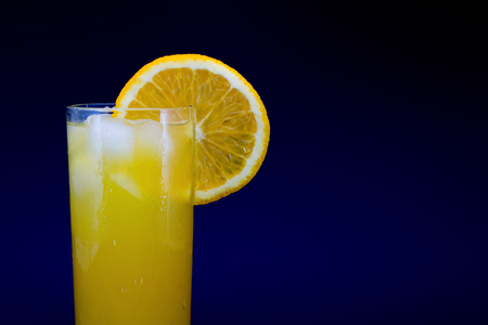 Glass of fresh orange juice with ice and a slice of orange isolated on a black backgroundの写真素材