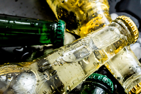 Beer in bottles with bubbles in ice cubes closeup on a dark backgroundの写真素材