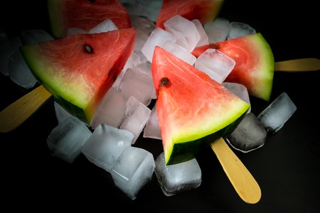 watermelon cut slice on a stick from ice cream in ice cube close-up on a black backgroundの写真素材