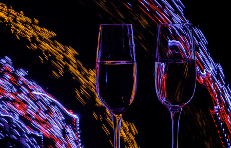 Two glasses of champagne wine on a background of abstract colored lights in motionの写真素材