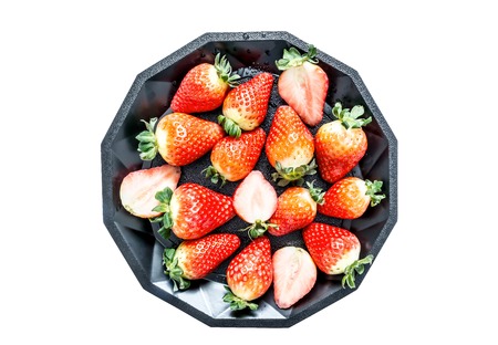 Strawberry with leaves on a black plate isolated on white backgroundの写真素材