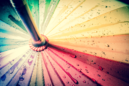 Multi-colored colorful umbrella with all colors of the rainbow with raindrops. Vintage, grunge, old, retro style photo.の写真素材