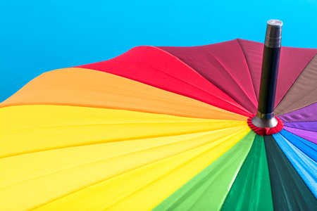 Multi-colored colorful umbrella with all colors of the rainbow on a blue background. Bright texture background.の写真素材