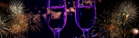 Two glasses of wine sizzling champagne with bubbles close-up on the background of colorful fireworks