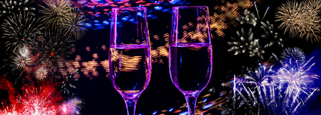 Two glasses of wine sizzling champagne with bubbles close-up on the background of colorful fireworksの写真素材