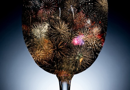 Colorful fireworks against the black silhouette of a wine glass closeup. Fireworks inside the...