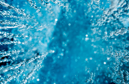Abstract background of water pouring from above with sun highlights on the drops. Falling rain drops with sunshine. View from above.の写真素材