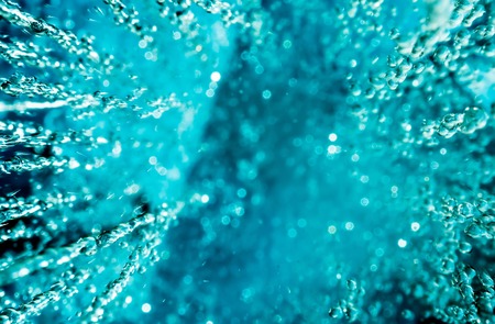 Abstract background of water pouring from above with sun highlights on the drops. Falling rain drops with sunshine. View from above.の写真素材