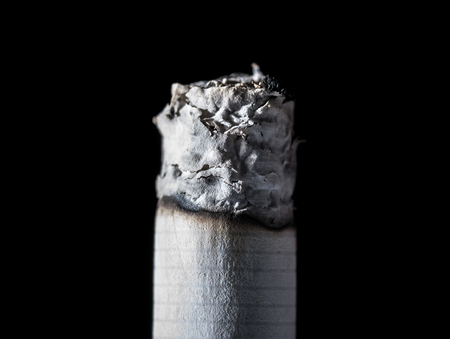 Burning smoldering cigarette close-up isolated on black backgroundの写真素材