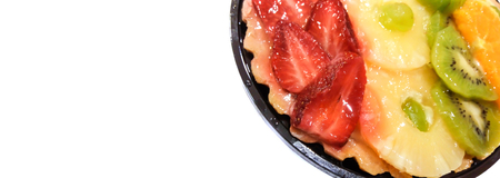 Fruit cake with oranges, kiwi, grapes, pineapple and strawberries closeup isolated on white background with place for text. view from above.の写真素材