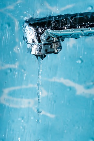 Water flows from a modern chromed water tap faucet macro close-up.の写真素材