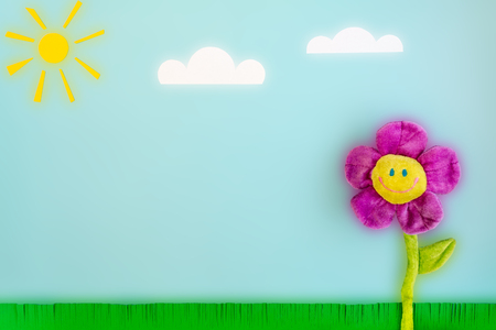 Paper sun, clouds, green grass and toy big flower with a smiling face on a blue background. Funny summer landscape composition with a luminous effect on the theme of good sunny weather and good mood.の写真素材
