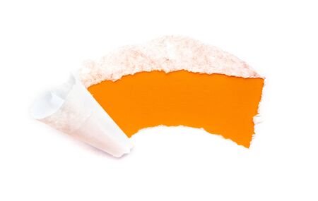 A hole in white paper with torn edges isolated on a white background with a bright orange color paper background inside.の写真素材