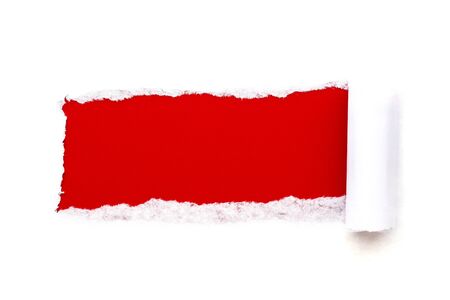 A hole in white paper with torn edges isolated on a white background with a bright red color paper background inside. Good paper texture.の写真素材