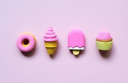 Different toy sweets in miniature with shadows close-up on a soft pink color background.