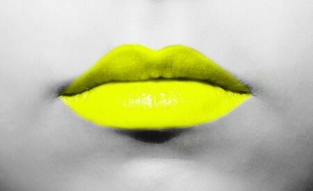 Female lips close-up with light yellow lipstick bright juicy color on a background of black and white face.の写真素材