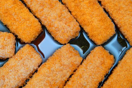 Frozen fish fingers on the frying panの写真素材