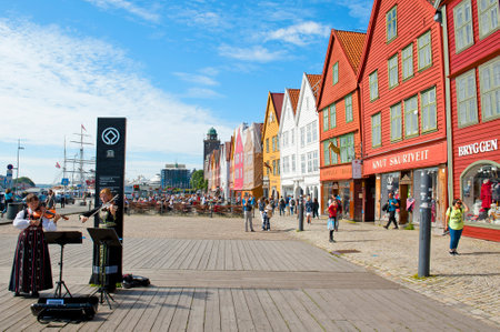 BERGEN, NORWAY - JULY 15, 2018: Two Norwegian girls in national costumes playing violin at Bryggen - the Hanseatic commercial buildings included on UNESCO`s World Heritage Listのeditorial素材