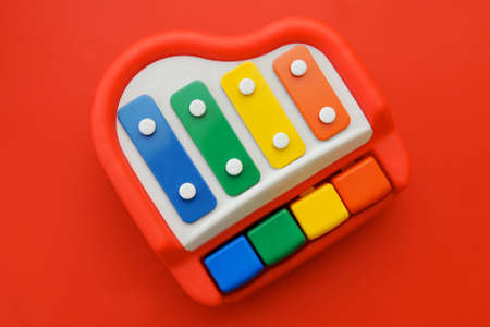 Top view of little cute colorful piano toy isolated on red backgroundの写真素材