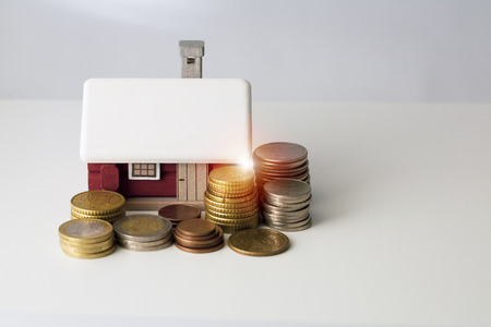 Mortgage loan and real estate tax macro financial Concept, Scandinavian house model and pile of coins money on brown wooden frame, with copy space in middle of the frame.の写真素材