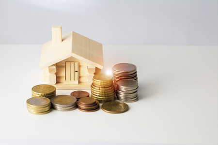 Mortgage loan and real estate tax macro financial Concept, Scandinavian house model and pile of coins money on brown wooden frame, with copy space in middle of the frame.の写真素材