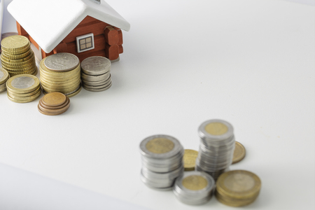 Mortgage loan and real estate tax macro financial Concept, Scandinavian house model and pile of coins money on brown wooden frame, with copy space in middle of the frame.の写真素材