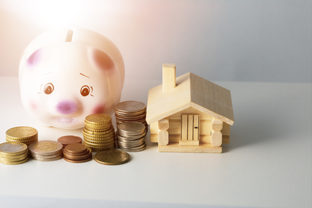 Mortgage loan and real estate tax macro financial Concept, Scandinavian house model and pile of coins money on brown wooden frame, with copy space in middle of the frame.の写真素材
