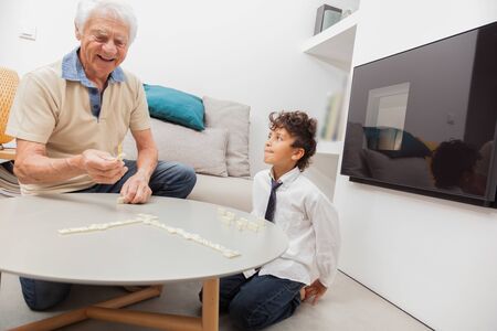 Grandfather and grandson playing game Dominoes.の写真素材