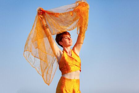 FREEDOM, MOVEMENTS, WOMAN ON A GATEWAY WITH A ORANGE SCARF