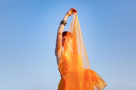 FREEDOM, MOVEMENTS, WOMAN ON A GATEWAY WITH A ORANGE SCARF