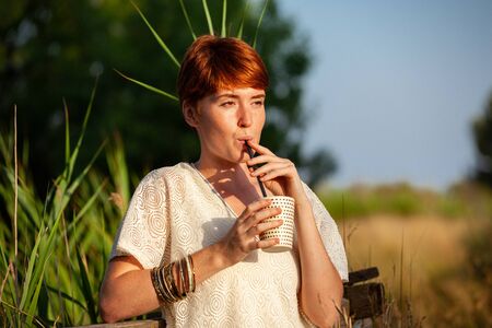 WOMAN DRINKING STRAW IN THE COUNTRYSIDEの写真素材